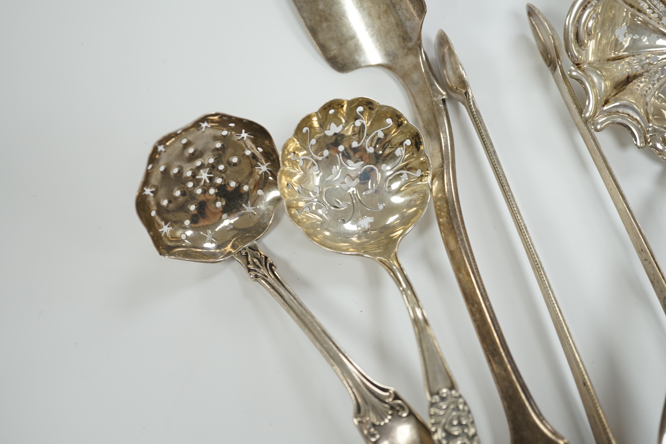 A Victorian silver fiddle pattern stilton scoop, London, 1847, 21.5cm and six other items of sundry flatware including Dutch white metal sifter spoon, smaller silver sifter spoons and a pair of Georgian silver sugar tong